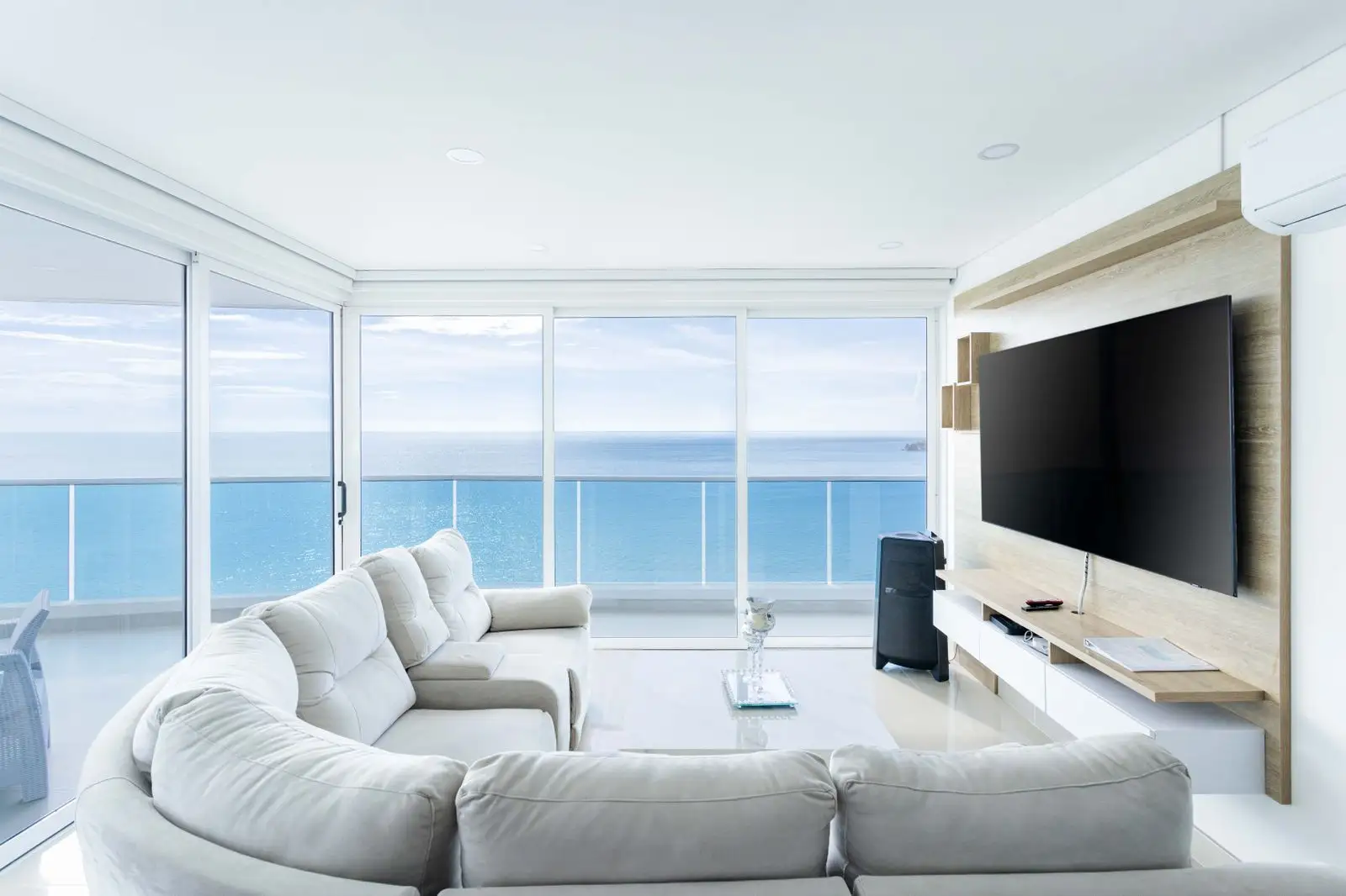 Bright short-term rental condo living room with a white sectional sofa and floor-to-ceiling windows onto the ocean
