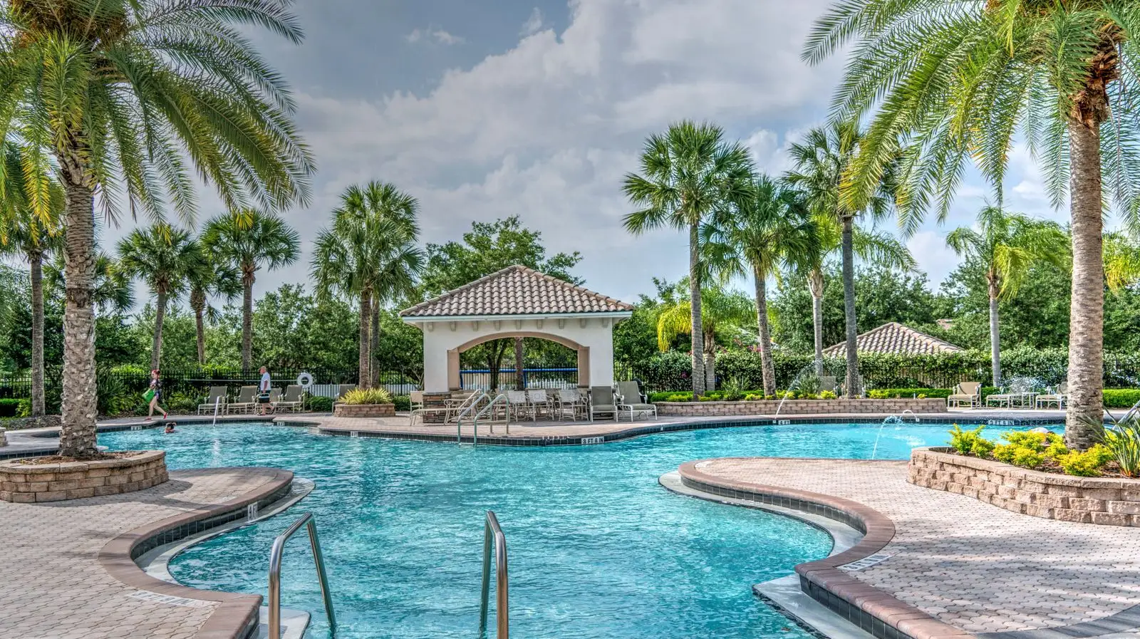 Resort-style pool with palm trees and a tiled-roof gazebo — the kind of vacation rental community we manage in Florida